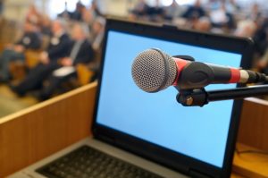 Microphone and laptop screen at the Conference. Microphone and blank laptop screen against the background of conference hall.